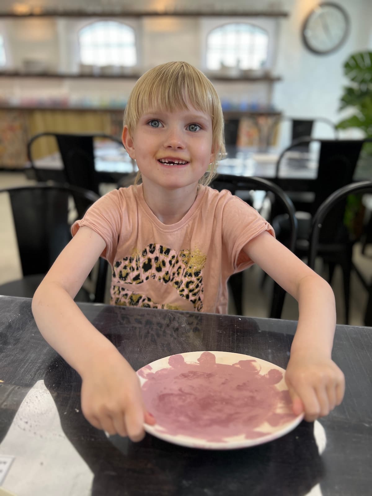 En glad ung pige viser stolt sin tallerken frem hos Funart keramik, som er perfekt til familieoplevelser Nordjylland.
